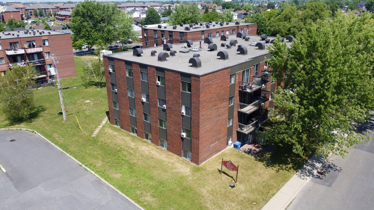 7315 avenue Chauvin seen from above at the street corner, with the building's sign on the lawn