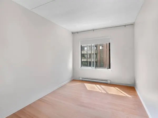 Empty bedroom with a window and sunlight on the floor.