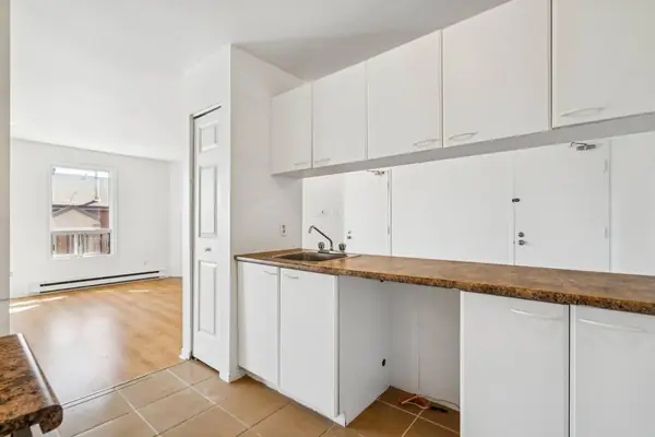 Kitchen counter with white cabinets, and a room with a window beyond