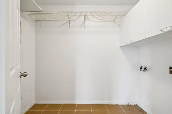 Storage room with a wire shelf, cabinets and laundry hookups