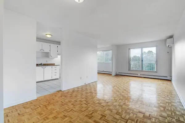 Living area with parquet floor, the kitchen on the left and two windows