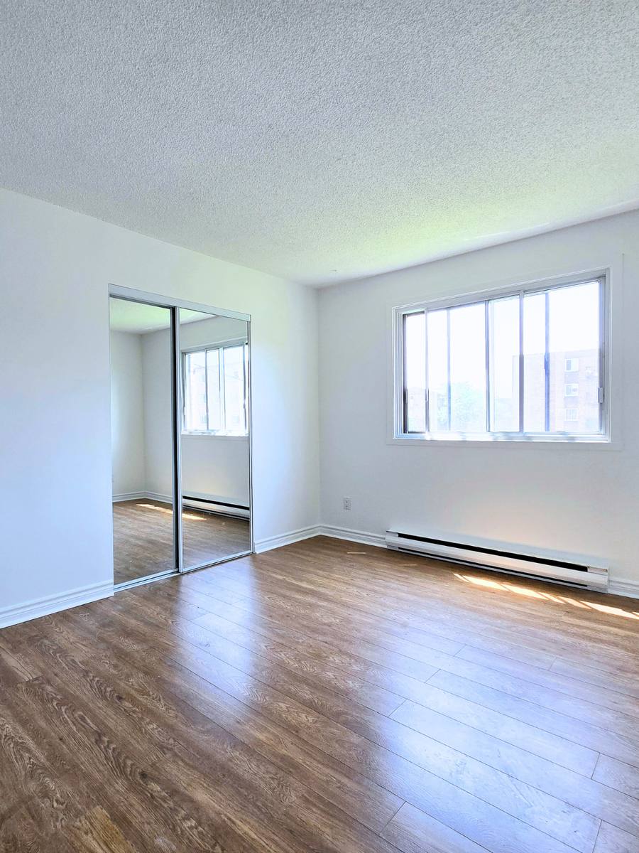 Empty main bedroom with a mirrored closet and a window in the 5½