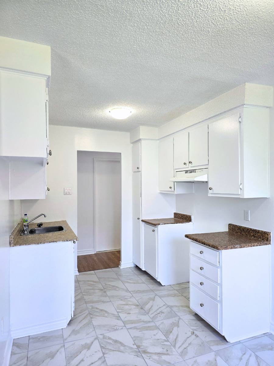 Kitchen with white cabinets and a tiled floor, looking toward the doorway in the 5½