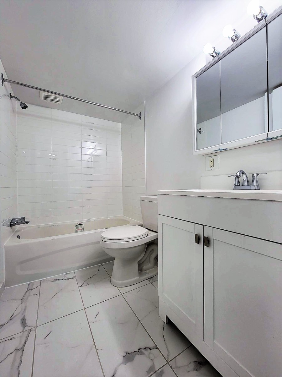 Salle de bain avec baignoire et pharmacie à miroir