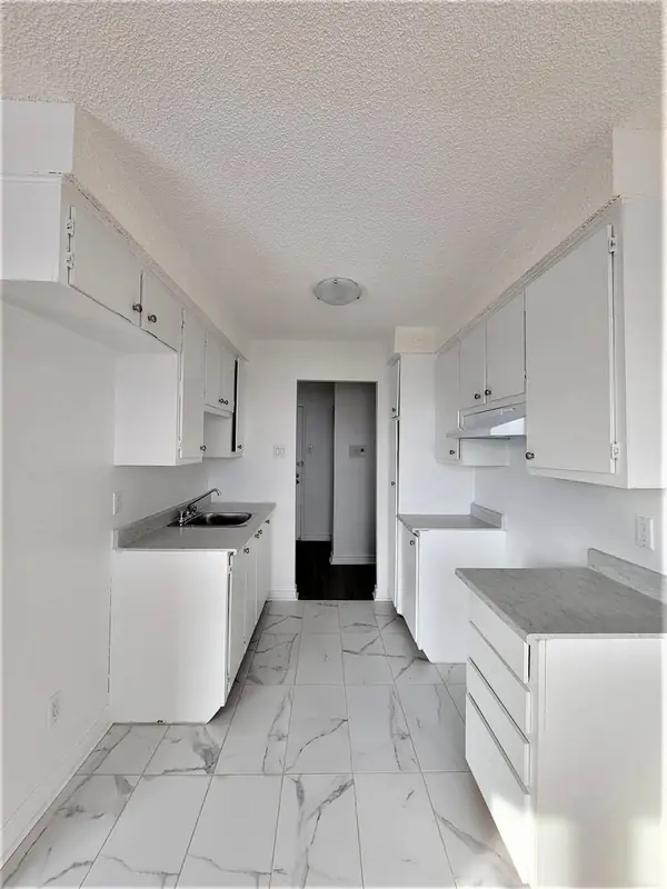 Cuisine en couloir vue vers l'entrée, avec plancher de céramique
