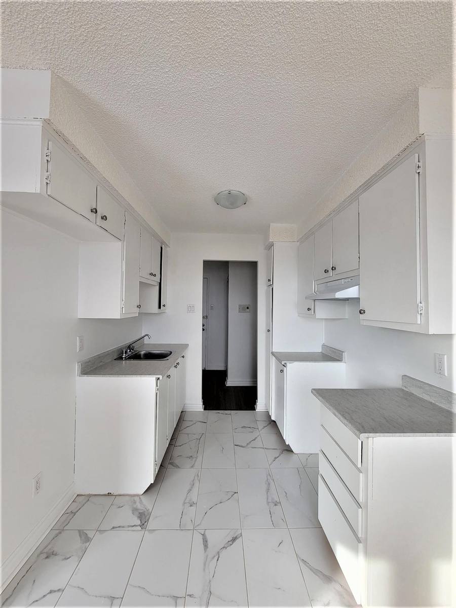 Galley kitchen looking toward the entrance, with a tiled floor