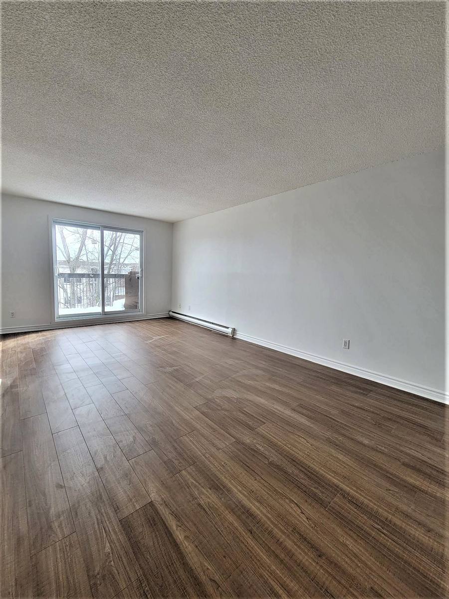 Living room seen from the far end, looking toward the balcony door