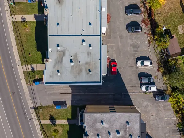 The roofs, the lawn by the boulevard and the parking, seen from straight above