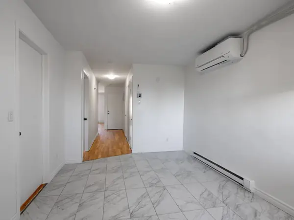 Tiled kitchen area with a wall-mounted air conditioner, looking toward the hall