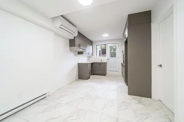 Long kitchen with grey cabinets and a wall-mounted air conditioner