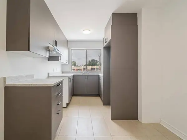 Kitchen with dark cabinets and a window at the end in the 4½, photographed empty