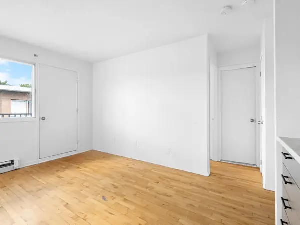 Living room with wood floor, looking toward the balcony door and the inner door